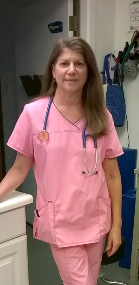 Female veterinarian in pink scrubs with stethoscope in clinic hallway